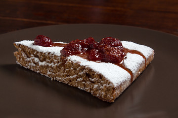 A piece of cake with strawberry jam and sugar. Dessert, food, sweet, baking. Biscuit, brownie, tiramisu, cheesecake. Cook at home, homemade, closeup, Bakery products.