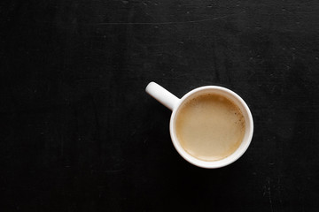 top view of white cup with coffee on a black table