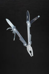 Multi-functional tool flying on a black background. The concept of an extended multi-tool with free space