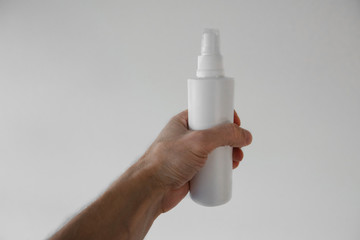 male hand holds a white spray on a white background