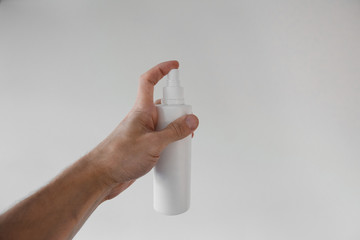 male hand holds a white spray on a white background