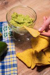The family eats traditional Mexican guacamole sauce with chips, top view. Vegan snack from unhealthy and healthy foods