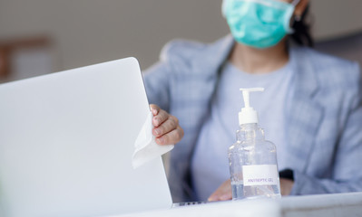 Fototapeta premium Worker disinfects and cleans the laptop and keyboard with antibacterial wet wipes to protect against corona virus covid-19 during pandemic outbreak. Hygiene and virus prevention at work or at home