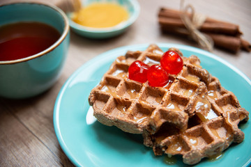 Healthy breakfast waffles with honey and coctail cherries