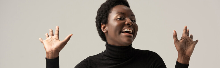 panoramic shot of cheerful african american woman in black turtleneck isolated on grey