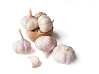 Garlic in wooden bowl and pile garlic cloves isolated on white background.