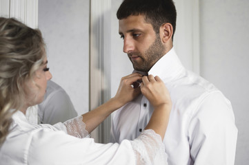 morning of the bride and groom. the bride helps to dress the groom on the wedding day. selective focus.film grain.