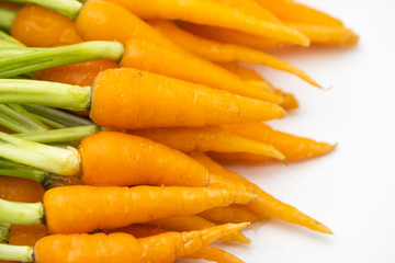 Pile of fresh raw baby carrots with green leaves isolated on white background, vegetable food concept