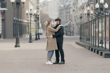 Young couple in love in the empty streets in medical masks. Virus protection concept