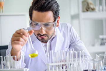 	 Attractive happiness scientist man lab technician assistant analyzing sample in test tube at laboratory. Medical, pharmaceutical and scientific research and development concept.