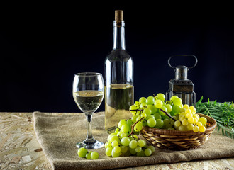 Bottles of wine, glassful and grapes on a black background close-up
