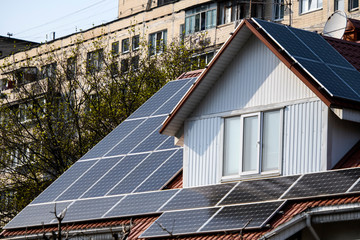 The cottage is equipped with solar panels on the roof with the apartment building behind. Ukraine.