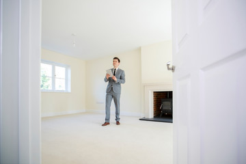 Realtor With Digital Tablet Looking Around And Valuing New Home