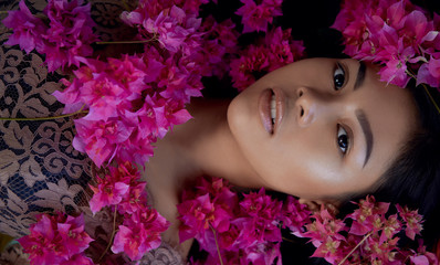 Asian girl portrait face in pink flowers. Beautiful Balinese women. Beauty salon and massage spa concept