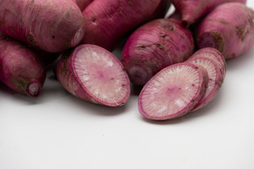 Pile of whole and sliced purple daikon radish isolated on white background