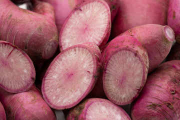 Pile of whole and sliced purple daikon radish isolated on white background