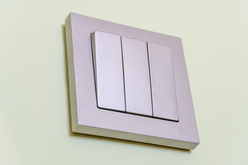 Triple grey wall light switch on a light green wall