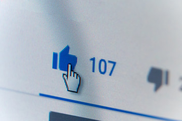 Cursor on the Thumbs up button close-up on the monitor screen, background