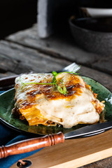 Piece of tasty hot lasagna with red wine. Small depth of field. Traditional italian lasagna. Portion. Italian food. Food on green plate. Bolognese sauce. Bechamel sauce. Still life of food.