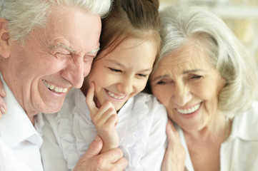 Close up portrait of happy senior couple with granddaughter at home