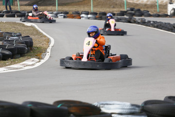 girl is driving Go-kart car with speed in a playground racing track.