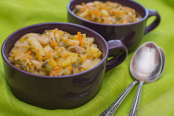 Traditional Russian sauerkraut soup in a purple porcelain cup on a green napkin.
