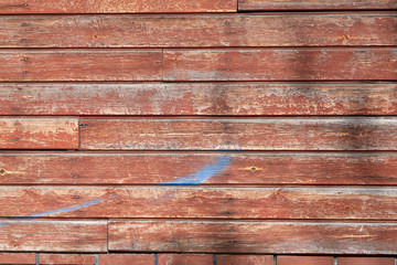 Wooden texture from boards with peeling red paint.