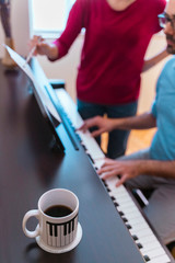 Vertical detail of teacher explaining classical keyboard morning class with coffee at home. Student...