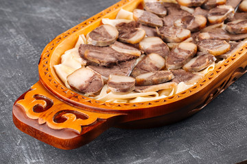 Kazakh national dish Beshbarmak on a wooden traditional plate, side view, horizontal, closeup, Central Asian cuisine