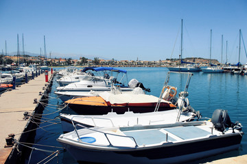 A group of boats are docked next to a wooden berth in a summer time