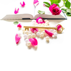 Pink Bible flat lay: Pearls, pink rose petals and golden key on white table background . Pink roses. Top view, empty space for text. Mock-up. Copy space.