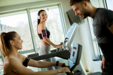 Fototapeta na wymiar Young woman using treadmill in modern gym