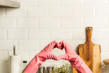 Corazón hecho de guantes de protección de color rosa sobre fondo blanco de cocina ... Manos de mujer con guantes de protección. Concepto de cocina limpia. Vista de frente. Copy space © Mercedes Fittipaldi