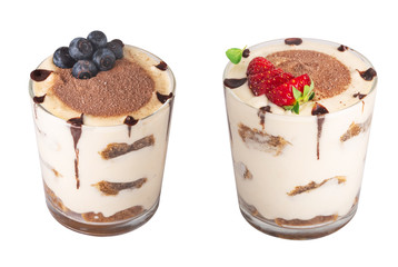 tiramisu in a glass with berries, mint and coffee beans on a light wooden background