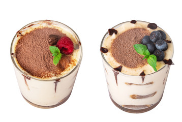 tiramisu in a glass with berries, mint and coffee beans on a light wooden background
