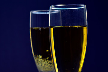 Two yellow glasses of champagne on a dark background