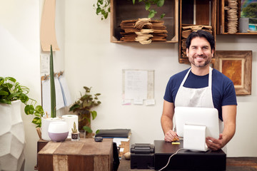 Portrait Of Smiling Male Sales Assistant Standing Behind Sales Desk Of Florists Store