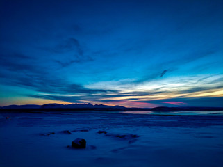 Enjoying the sunrise with this great combination of colours such us blue, red and yellow; a frozen lake as a background and surrounded by mountains