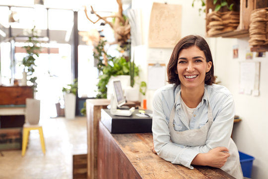 Portrait Of Smiling Female Sales Assistant Standing Behind Sales Desk Of Florists Store