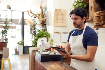 Fototapeta na wymiar Male Owner With Digital Tablet Standing Behind Sales Desk Of Florists Store