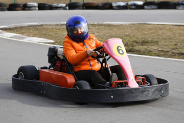 girl is driving Go-kart car with speed in a playground racing track.