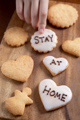 stay at homeと書かれたアイシングクッキーを持つ子供