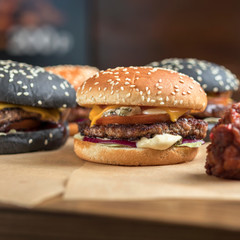 hamburgers with yellow and black rolls on parchment paper with breaded chicken wings and French fries