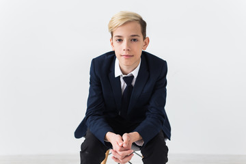 Portrait of stylish school boy teenager in white shirt and jacket against white background.