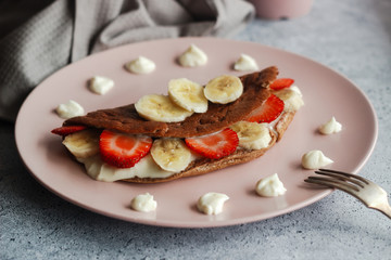 Delicious banana oatmeal pancake on a plate. Oatmeal pancake with cream cheese, banana and strawberries