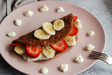 Delicious banana oatmeal pancake on a plate. Oatmeal pancake with cream cheese, banana and strawberries