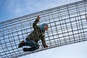 Fototapeta premium Little boy walking on a metal grid on the playground