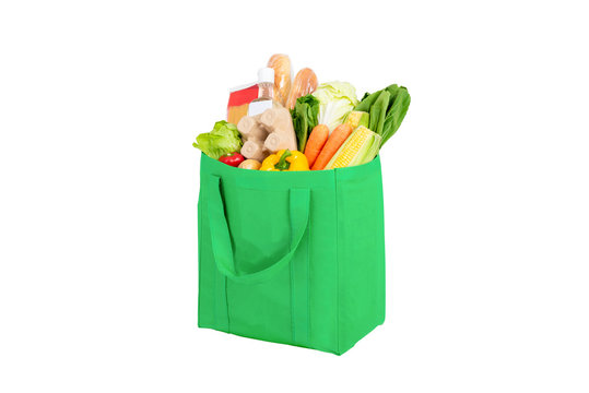 Green reusable shopping bag full of vegetables and groceries isolated on white background
