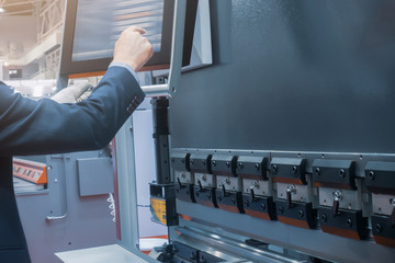 The operator presses buttons on the terminal for industrial sheet metal processing equipment