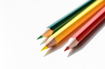 Three color pencils - red, yellow, green on a white background. Concept - school, education, art education